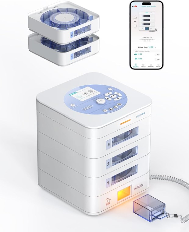 White, cube device with 3drawers and buttons on the top. Container attached to a to the machine with a cord is at the bottom. Cell phone with app for the device is also visible.