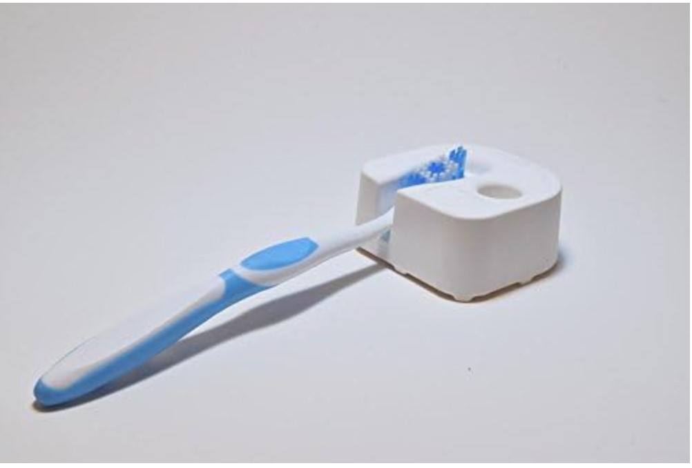 Blue and white toothbrush laying in a supportive hard, white foam cradle