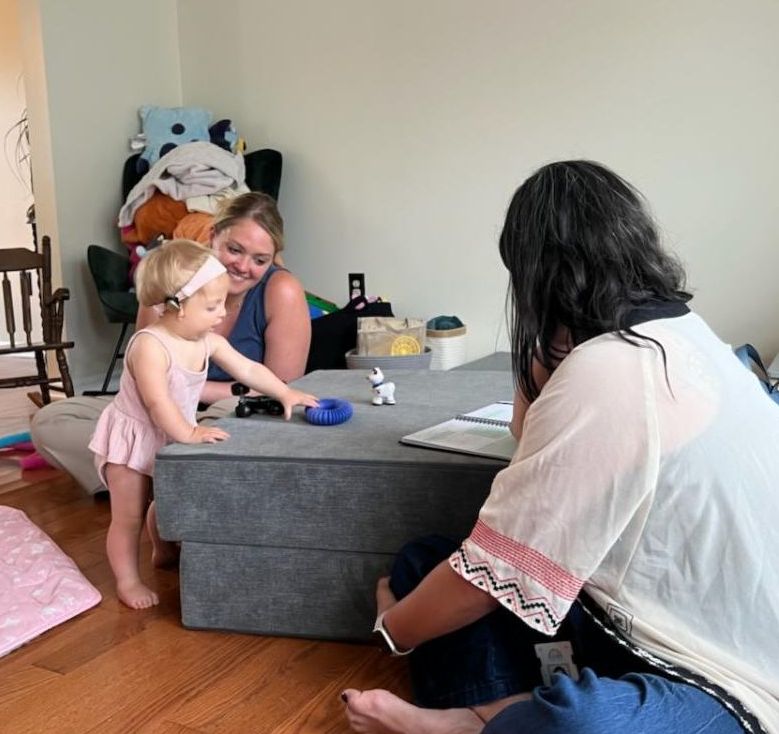 mom smiles at daughter playing with blocks