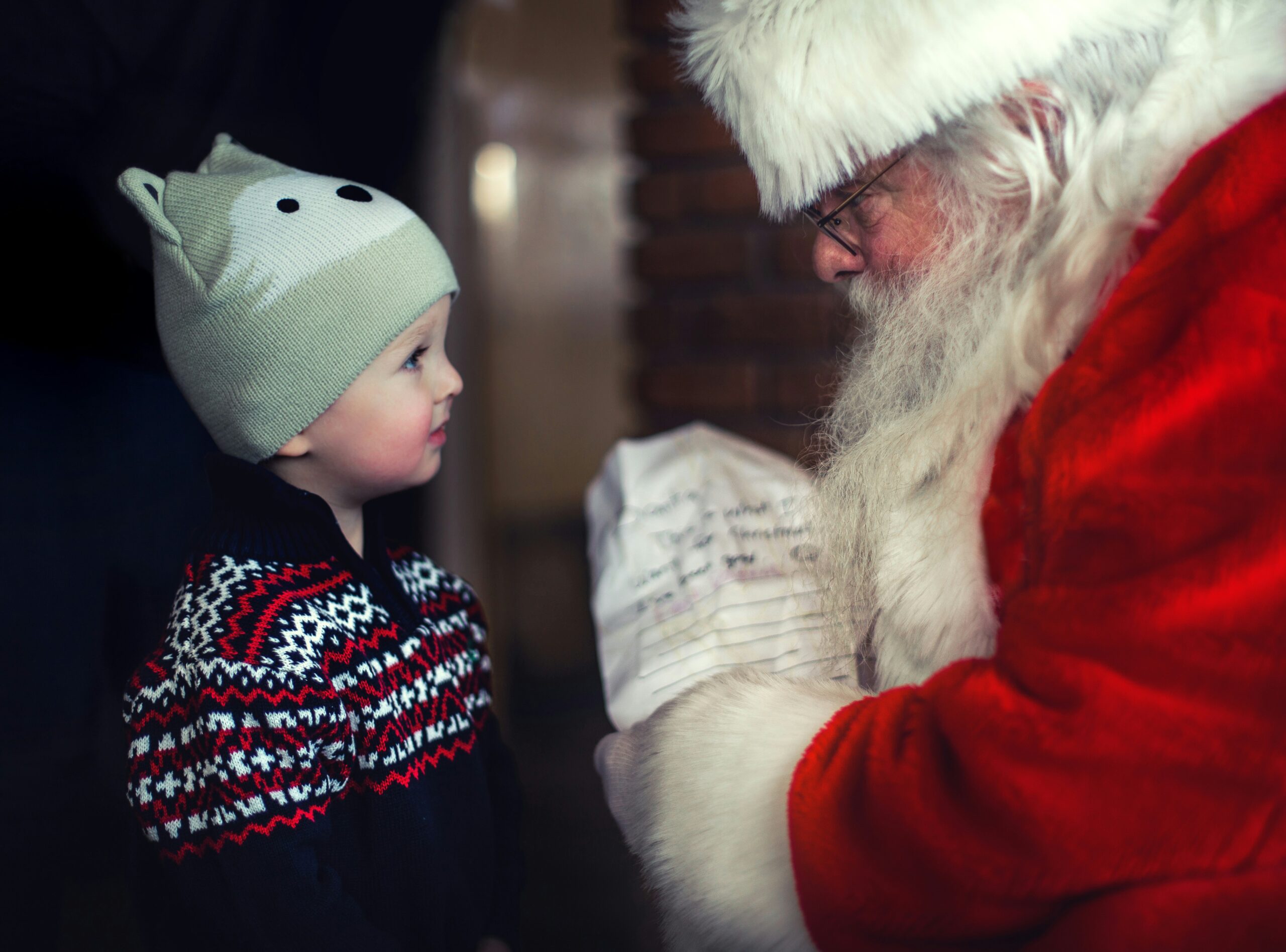 Santa talking to a little boy while holding a list