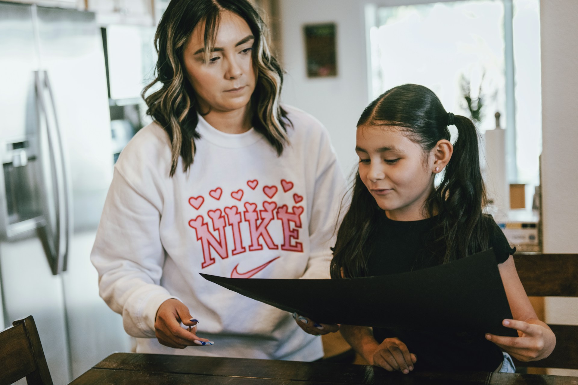 Image of Mom and daughter looking at a paper standing in a kitchen