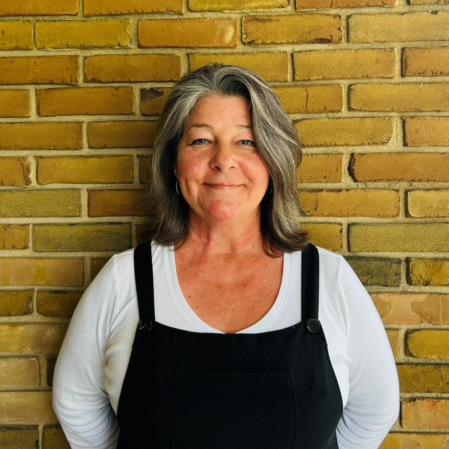 Image of a woman with salt and pepper hear smiling