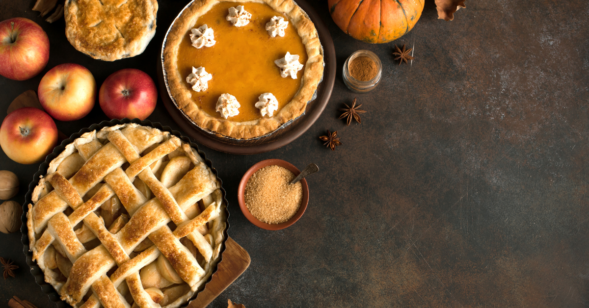 Imagen de archivo en la que se ven tartas de manzana, tartas de calabaza y adornos de calabaza sobre una mesa.